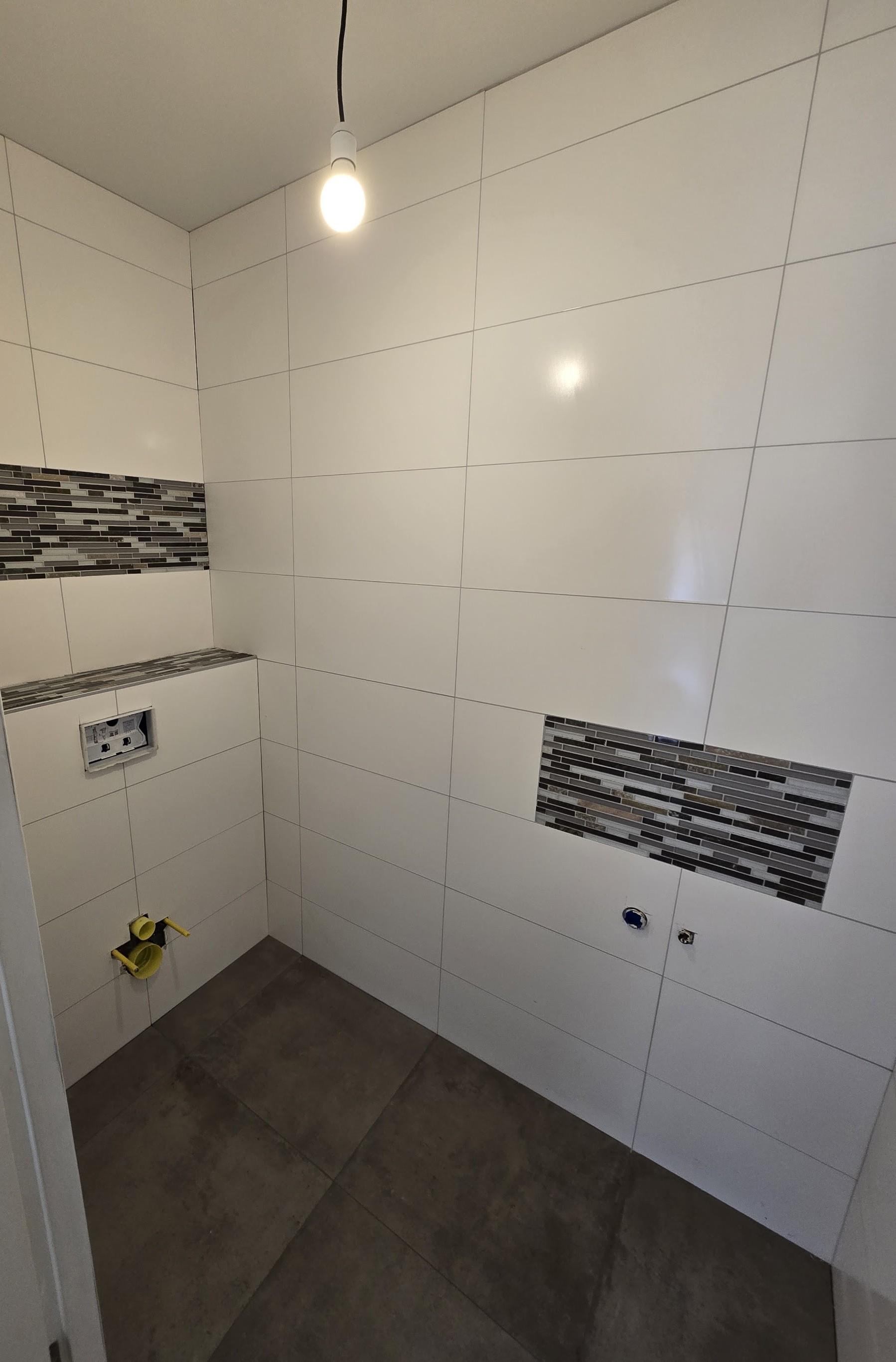 Toilet met witte wandtegels, twee mozaïekstroken en een donkere vloer